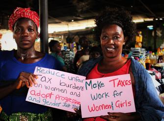 Chairlady and Market Woman pose with Placards during the sensitization on Tax