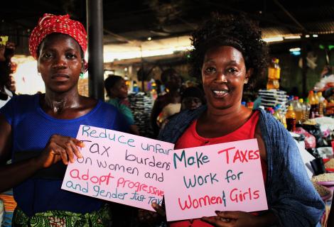 Chairlady and Market Woman pose with Placards during the sensitization on Tax